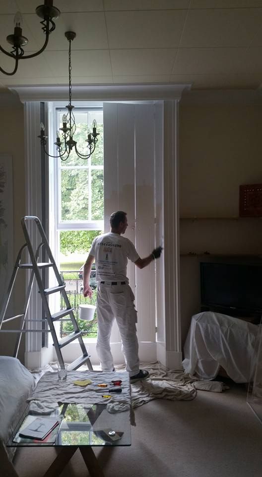 A man decorating and painting a window frame
