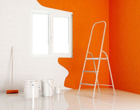 Paint equipment and half painted wall in bright orange 
